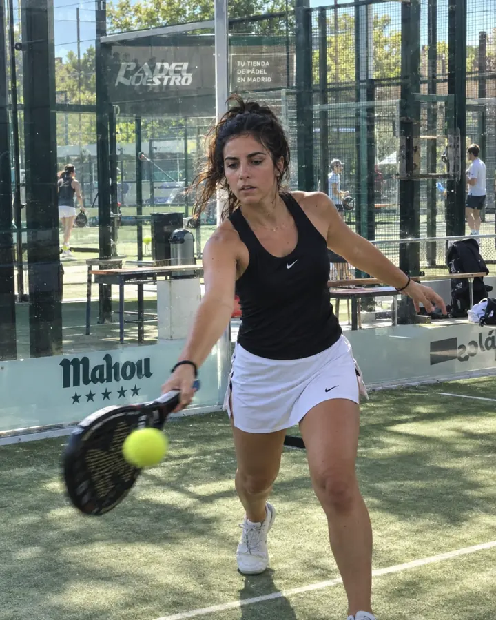 Chica jugando al pádel en una pista de cristal de un club de Madrid.