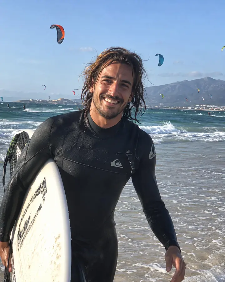 Chico saliendo del agua con la tabla de surf en Tarifa.